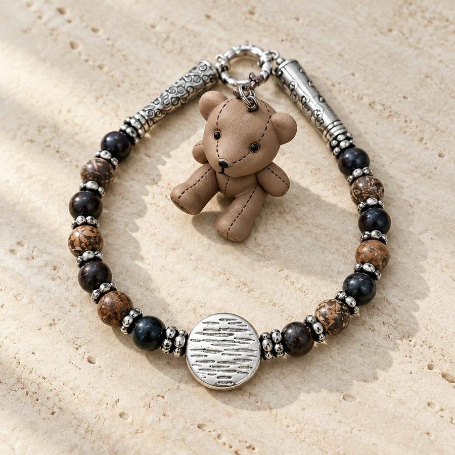 Close-up of the bracelet: jasper and onyx stones, silver beads, engraved medallion and figurine hanging from the clasp